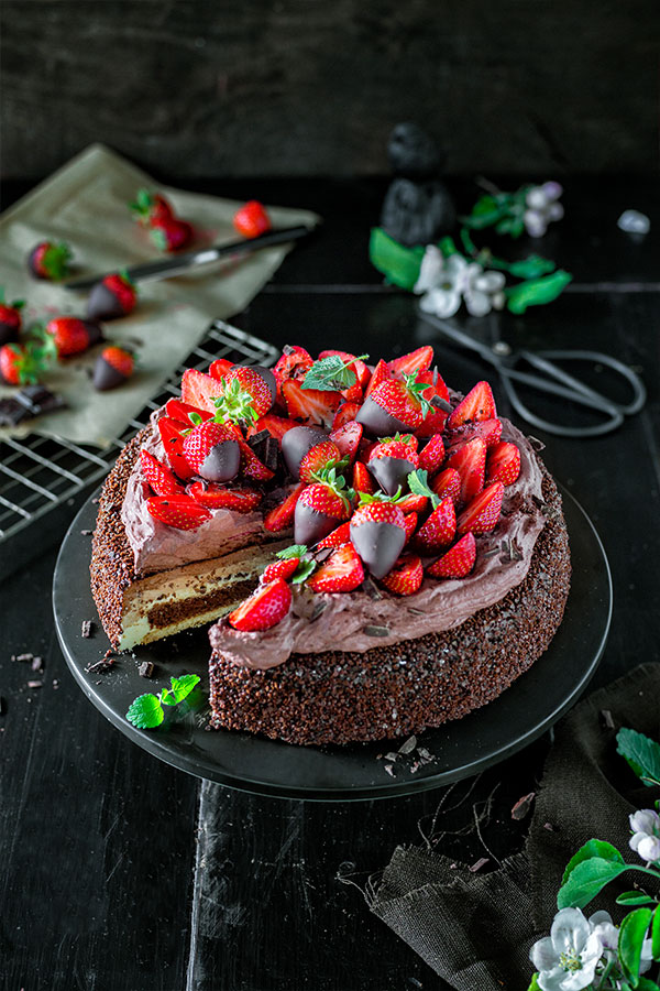 Schokoladentorte mit Erdbeeren verziert auf schwarzem Teller